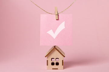 The concept of real estate services. Bargain home purchase. Small wooden house on a pink background	