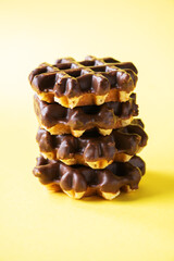 Stack of chocolate waffles. Close up and yellow background, copy space.