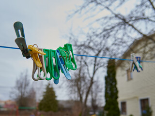 Colorful clothespins on a rope on a background of a spring garden.