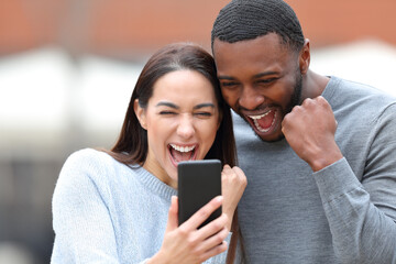 Excited interracial couple checking smart phone