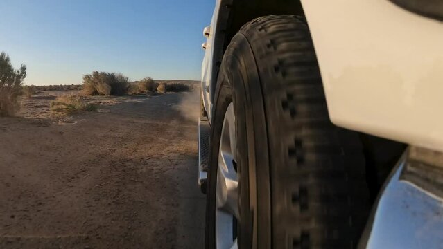 Low angle view from in front of the tire while driving down a bumpy road in the Mojave Desert at sunset