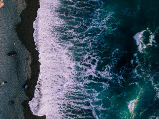 Large sea waves are foaming, hitting the sandy shore. Emerald water. Evening summer sea. Wet sand. Rough sea.