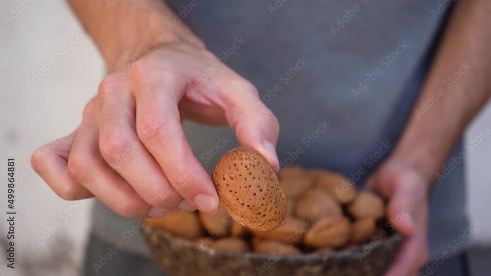 Poster man showing almond nuts in shell on camera. - close up