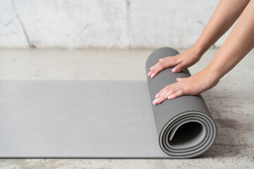 Close up of hands rolling mat after yoga class on the floor
