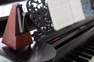 closeup of wooden metronome on an old black piano