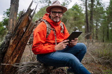 Man using a tablet in the forest.
