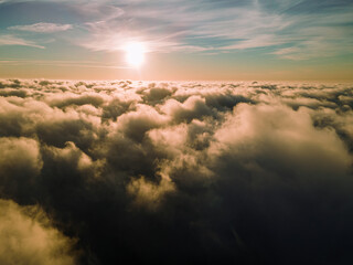 Fototapeta premium A magical sunset over the clouds. The rays of the sun beautifully pass through the clouds. Above the sky. Fluffy clouds at sunset thickly covered the sky. shooting at high altitude.