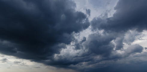 Naklejka na ściany i meble The dark sky with heavy clouds converging and a violent storm before the rain.Bad or moody weather sky and environment. carbon dioxide emissions, greenhouse effect, global warming, climate change.