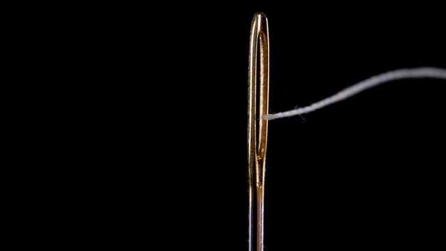 Thread for sewing is threaded into the eye of a needle. Sewing needle.