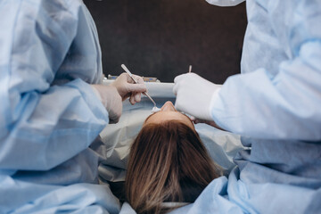 Surgeon and his assistant performing cosmetic surgery on nose in hospital operating room. Nose...