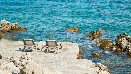 two sunbeds at a bathing place on the rocky coast of the Adriatic Sea near Krk in Croatia