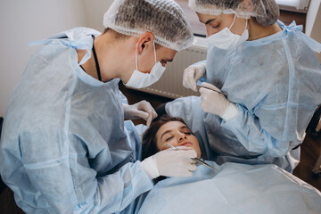 Obraz premium Surgeon and his assistant performing cosmetic surgery on nose in hospital operating room. Nose reshaping, augmentation. Rhinoplasty.