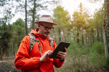 Man using a tablet in the forest.