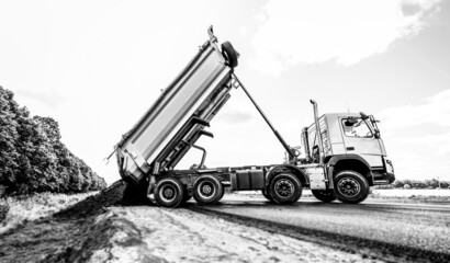 Fototapeta na wymiar Dumper truck unloading soil or groud at construction site. Road service build a new highway