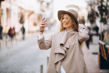 Woman with phone in hat outside the street