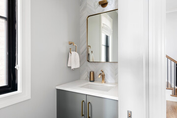 Contemporary White and Gray Half Bathroom. Gray bathroom vanity with gold fixtures and mirror...