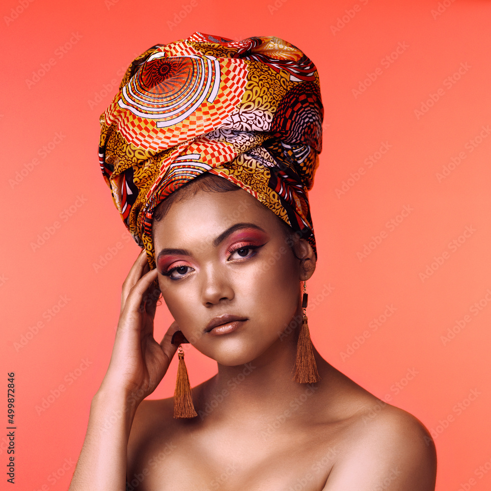 Canvas Prints If the crown fits, wear it. Studio shot of an attractive young woman wearing a traditional African head wrap posing against an orange background.