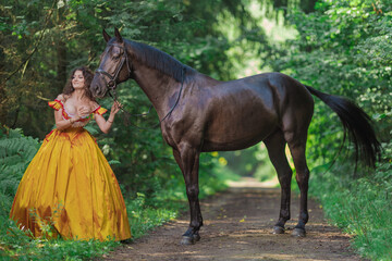 A young woman in a vintage yellow dress walks with a brown horse in a green park on a summer day