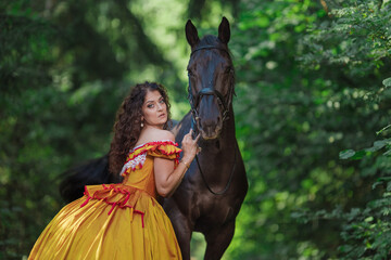 A young woman in a vintage yellow dress walks with a brown horse in a green park on a summer day