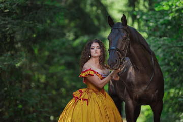 A young woman in a vintage yellow dress walks with a brown horse in a green park on a summer day