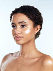 Do I have something on my face. Studio shot of an attractive young woman posing while applying cream to her face against a white background.