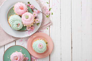 pink and green cupcakes with spring flowers on white wooden background