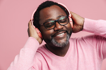 Obraz premium Black bearded man smiling while listening music with headphones