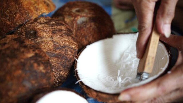 Hand scraping coconut, preparing coconut, grating coconut meat to prepare Thai desserts.