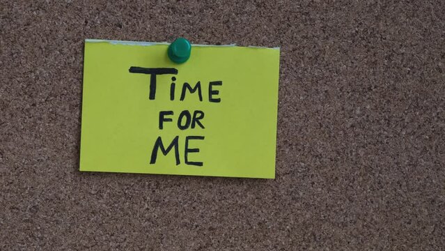 A sticky note with the words Time For ME on it pinned to a cork board. Close up.