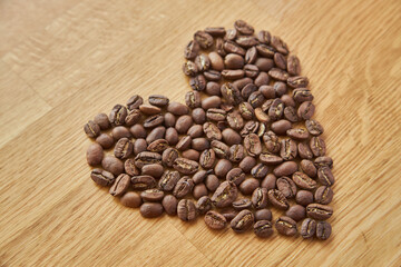 Closeup of heart shaped coffee beans, valentine heart of coffee, coffee grains. on wooden background