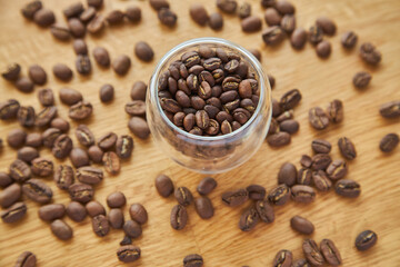 Coffee beans in a transparent bowl over a wood tablet with copy space.