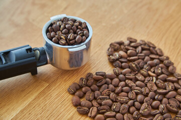 Black coffee beans seed in heart shape on brown wooden table, dark cofee arabica robusta roasted grain flavor aroma cafe, natural coffe shop background, top close up view from above,