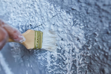 brush in hand paints the wall white paint