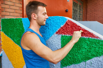 The guy paints the wall with a brush in bright colors