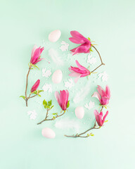 Creative arrangement in the shape of an egg made of magnolia flowers, Easter eggs and rabbits. Minimal flat lay concept. Easter and spring inspiration.