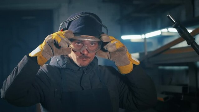 portrait shot of a tired factory worker. cutting metal structures, making homemade armor plates by professional workers using a cutting machine. cutting work with smooth equipment for steel metal