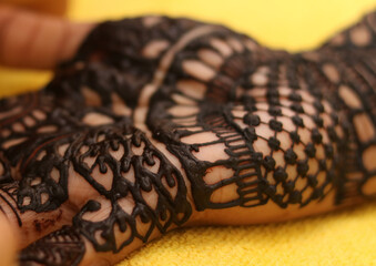 Performing mehandi or henna design on female hand close up image isolated