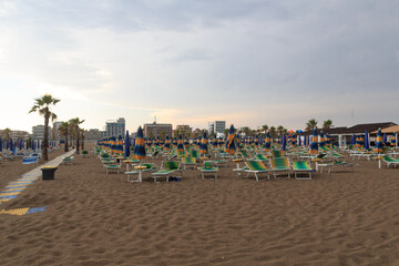 Fototapeta na wymiar Beach with sunshades and sun beds in seaside resort Sottomarina in Veneto, Italy