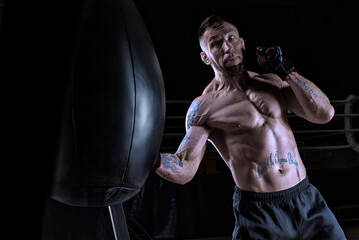 Fototapeta na wymiar Kickboxer hits the bag. Sports training. The concept of mixed martial arts.