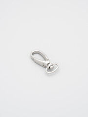 The heap of metal lobster claw clasp for making bags and backpacks lying on a gray background. Chrome-plated metal accessories and supplies for bags, backpacks. Handbags making, copy space