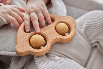 Close-up of a baby s hand, playing with a wooden toy. Unfocused background.