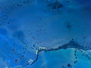 Abstract blue background with beautiful smudges and stains made with alcohol ink. Blue fluid texture resembles marble, stone, sea, ocean, space, watercolor or aquarelle.