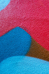 Fragment of the wall with blue red brown colors graffiti painting in the street. Part of colorful street art graffiti on wall background