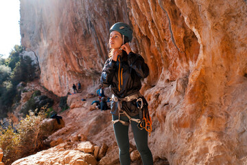 Girl, rock climber puts on a helmet on her head.