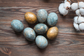 Marble Easter eggs on a wooden background with a cotton branch. Natural dyes. Happy Easter. High quality photo
