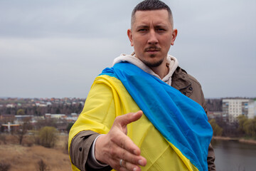 A man with the flag of Ukraine holds out his hand for a handshake