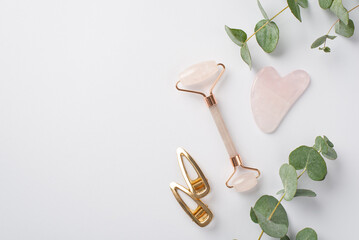 Skincare beauty concept. Top view photo of rose quartz roller gua sha massager gold hairpins and...