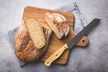 Sliced loaf of bread on cutting board. - obrazy, fototapety, plakaty