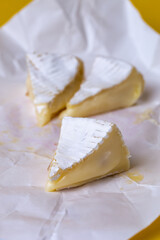 slices of sliced camembert cheese on yellow background.