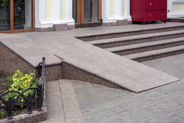 Ramped access, using wheelchair ramp for disabled people. Concrete ramp pathway near stone stairs...